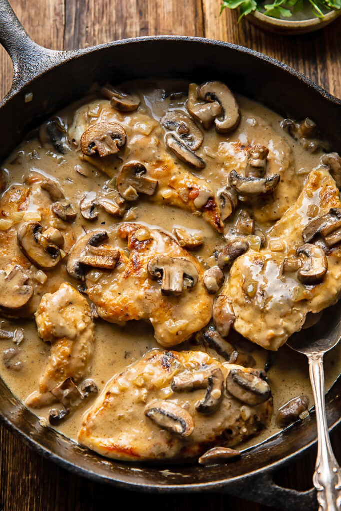 top down view of chicken and mushroom dish in a pan with a serving spoon in it.