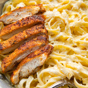 Top down shot of tagliatelle in alfredo sauce topped with blacken chicken strips in a bowl