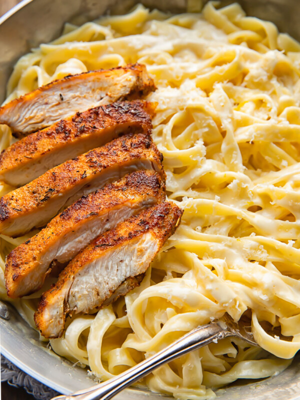 Top down shot of tagliatelle in alfredo sauce topped with blacken chicken strips in a bowl