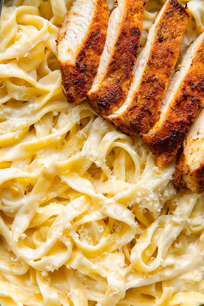 Close up shot of fettuccine pasta with alfredo sauce and blackened chicken