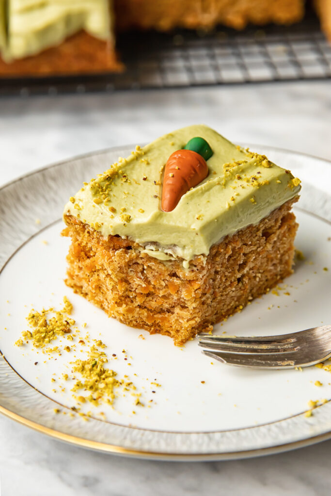 slice of carrot sheet cake on a plate with sprinkled pistachio