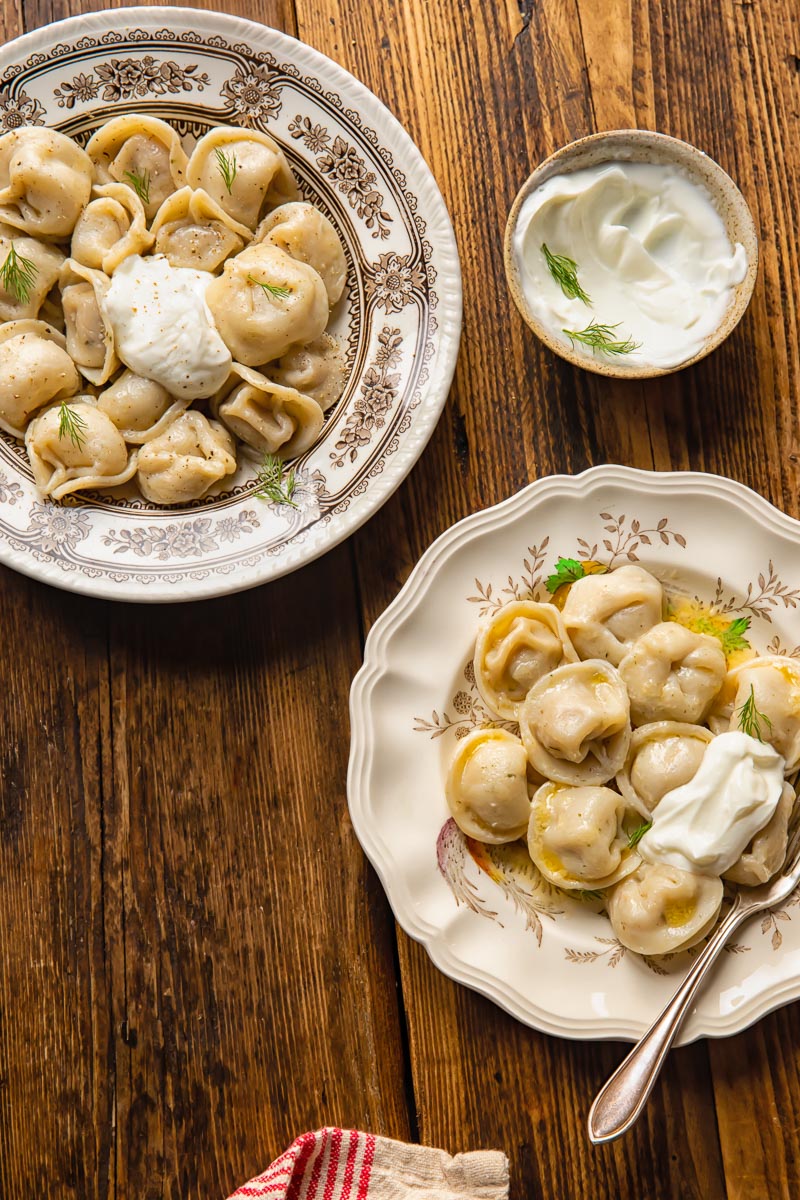 top down view of a bowl and a plate with pelmeni