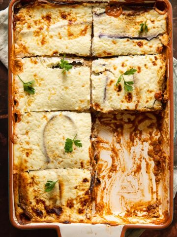 Vegetarian moussaka in a baking dish with pieces removed