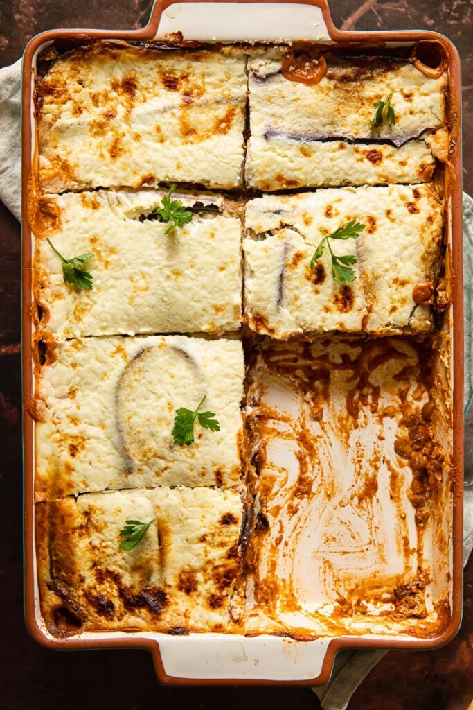 Vegetarian moussaka in a baking dish with pieces removed