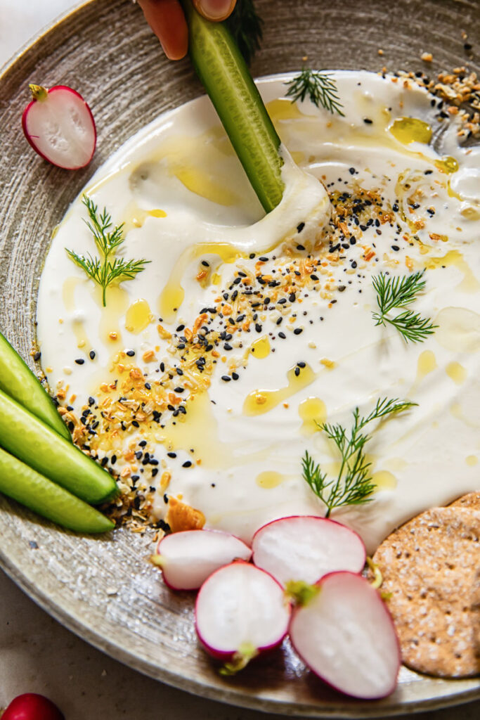 Close up of the whipped feta dip with a cucumber being dipped