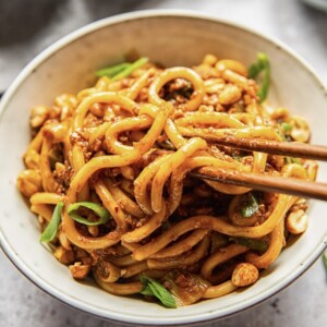 close up of a bowl of dan dan noodles with two chopsticks