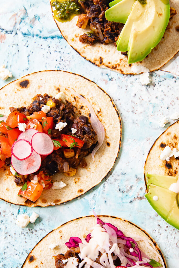 Black bean tacos with toppings including avocado, slaw and radishes