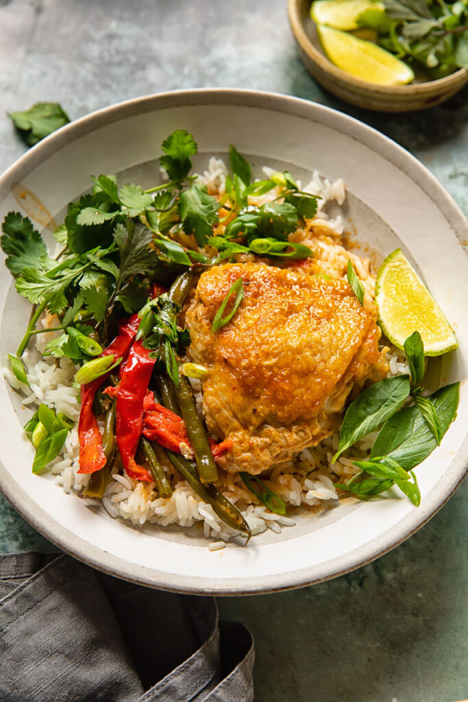 the coconut curry in a bowl with rice and chicken thigh