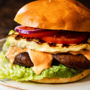 Side view of grilled halloumi burger with garlic red pepper aioli oozing down
