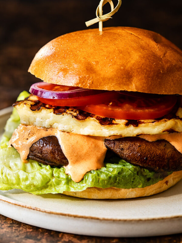 Side view of grilled halloumi burger with garlic red pepper aioli oozing down