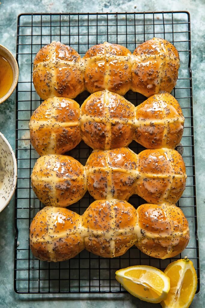 hot cross buns on a cooling rack with lemon slices