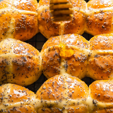honey being drizzled on top of a hot cross bun