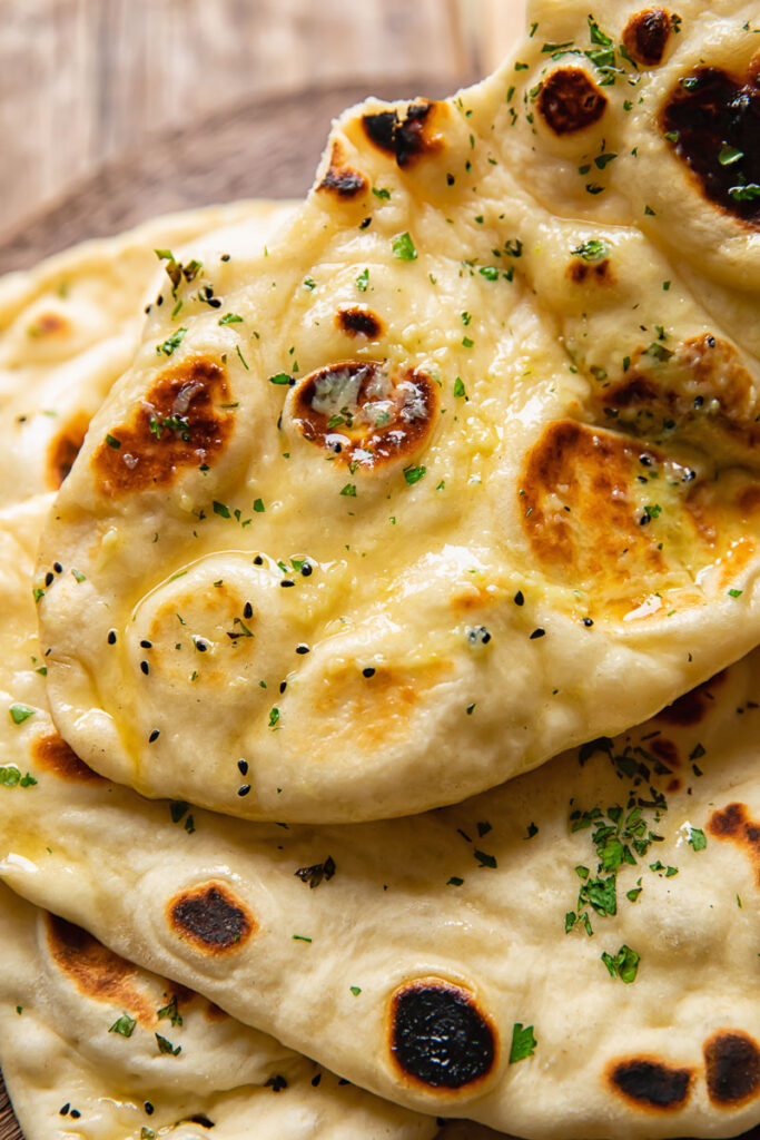 Top down shot of naan topped with herby garlic butter on a cutting board