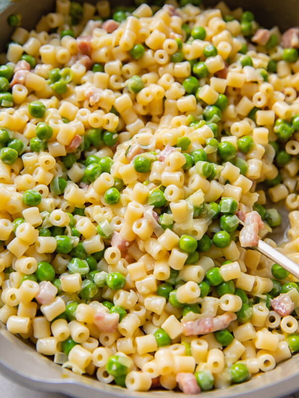 Close up shot of piselli pasta with peas and bacon bits in a large pan