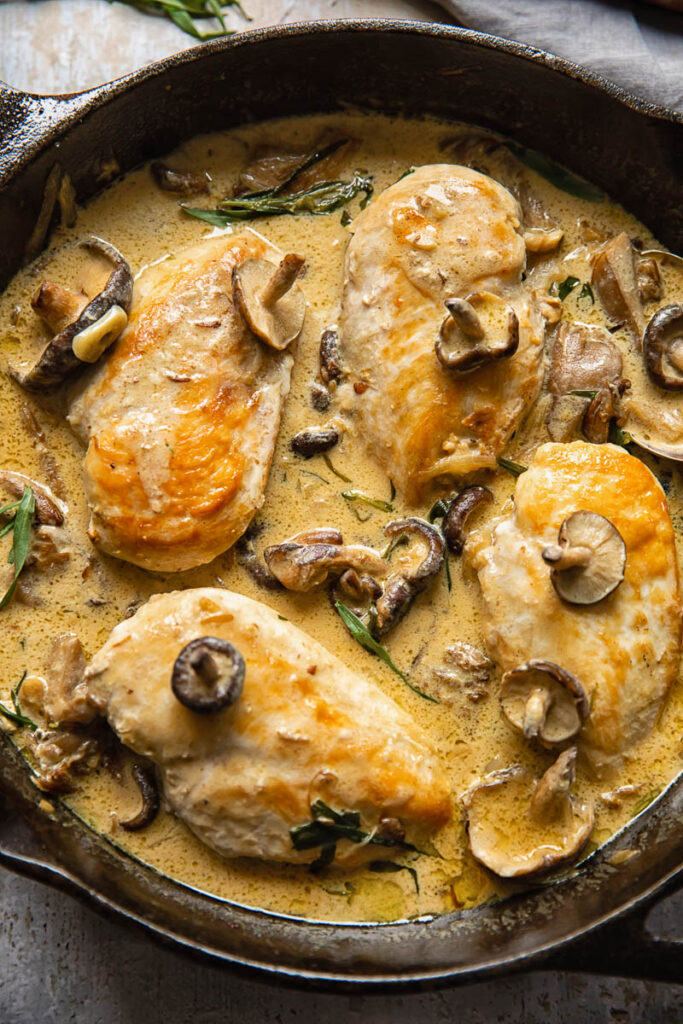 Top down shot of chicken breasts in a pan with creamy forestiere sauce and mushroom