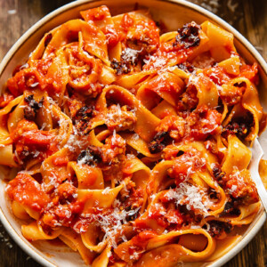 Close up shot of sausage ragu in a bowl with chilli crisp and Parmesan