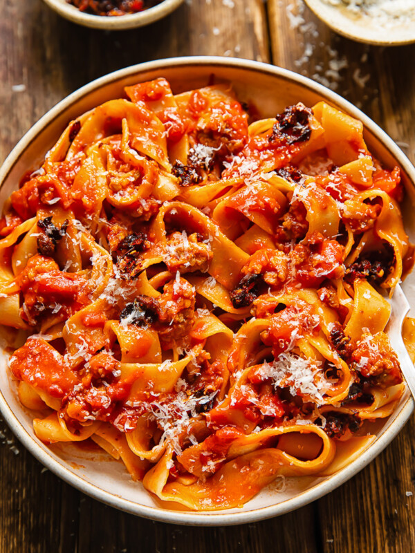 Close up shot of sausage ragu in a bowl with chilli crisp and Parmesan