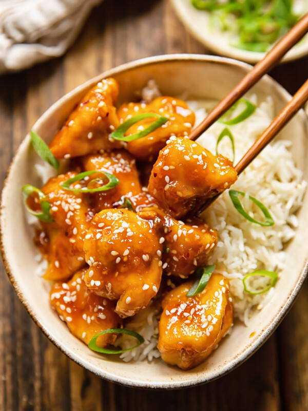 chopsticks removing piece of chicken from bowl of rice