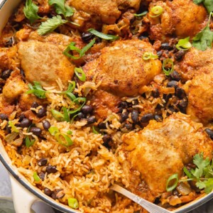 Top down shot of mexican chicken rice in a pan topped with black beans and cilantro