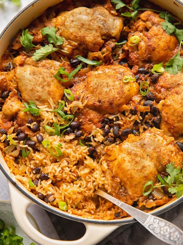 Top down shot of mexican chicken rice in a pan topped with black beans and cilantro