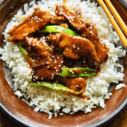 Top down shot of mongolian beef stir fry on a bed rice on a plate with chopsticks