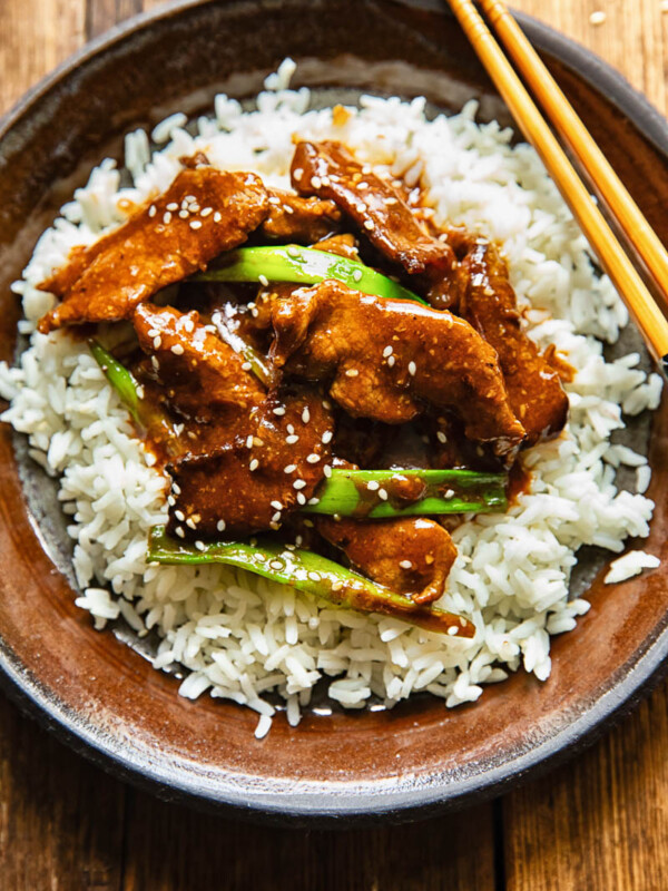 Top down shot of mongolian beef stir fry on a bed rice on a plate with chopsticks