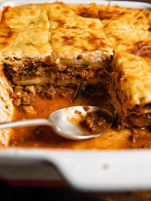 Close up shot of moussaka layers of beef and eggplant topped with creamy bechamel sauce along with a spoon