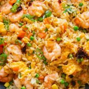 Close up shot of egg fried rice with shrimp carrots and peas, topped with green onions