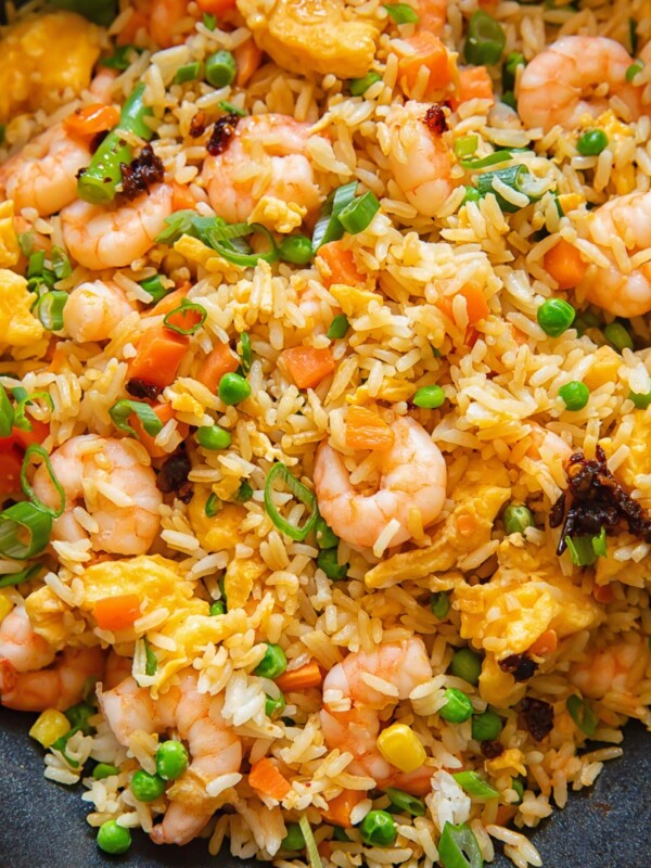 Close up shot of egg fried rice with shrimp carrots and peas, topped with green onions