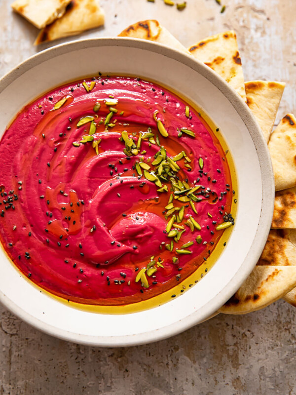 Bowl of beetroot borani with seeds, mint and flatbread