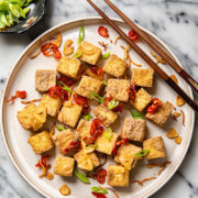 Plate of air fryer tofu bites with cop sticks and side dish of green onions