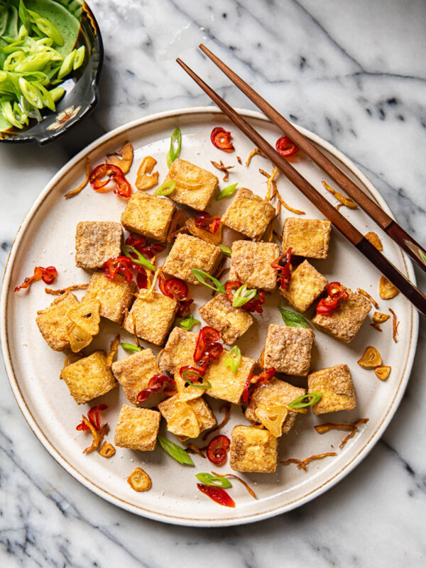 Plate of air fryer tofu bites with cop sticks and side dish of green onions