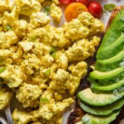 Plate of egg tofu scramble with avocado and tomatoes