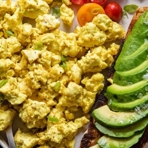 Plate of egg tofu scramble with avocado and tomatoes