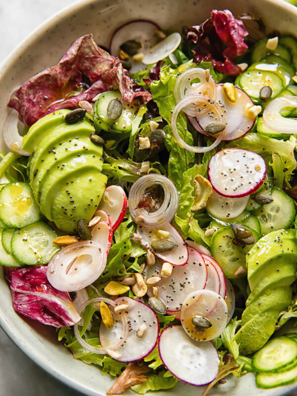 Close up shot of garden salad with radish, cucumber and avocado topped with nuts and seeds