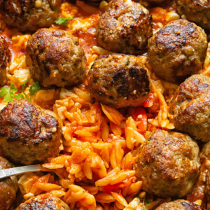 Close up shot of orzo baked in tomato sauce with meatballs