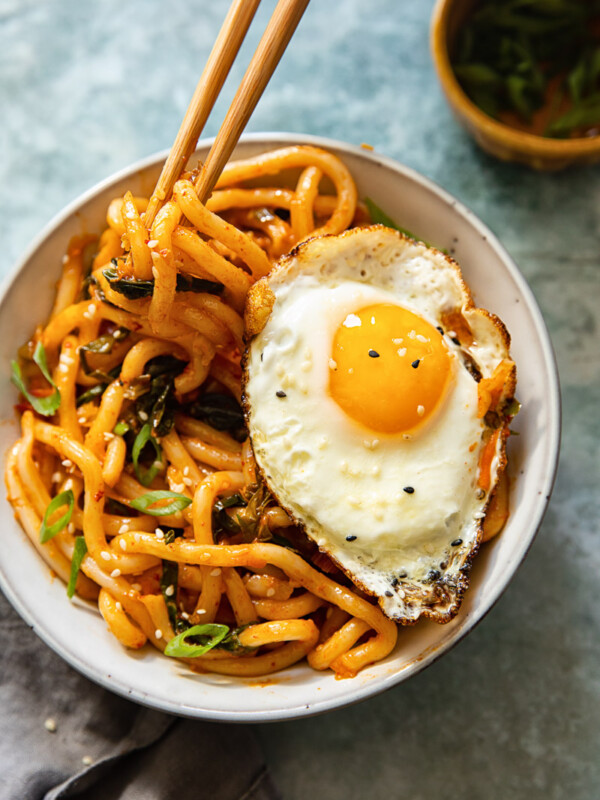Kimchi noodles in a bowl with a fried egg and chop sticks