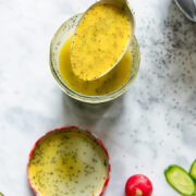 Top down shot of a spoon scooping poppyseed salad dressing out of a glass jar