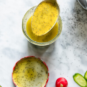 Top down shot of a spoon scooping poppyseed salad dressing out of a glass jar