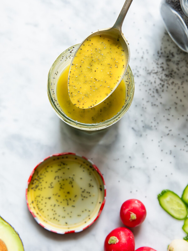 Top down shot of a spoon scooping poppyseed salad dressing out of a glass jar