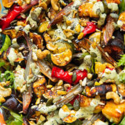 Close up shot of roasted zucchini, pepper and eggplant topped with nuts and tahini dressing