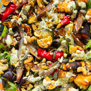 Close up shot of roasted zucchini, pepper and eggplant topped with nuts and tahini dressing
