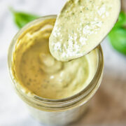 Close up shot of spoon serving tahini green goddess dressing into a glass jar