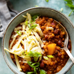 Bowl of vegetarian chili with grated cheese and spoon