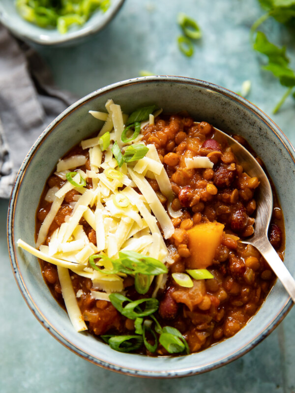 Bowl of vegetarian chili with grated cheese and spoon