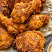 Close up shot of buttermilk fried chicken drumsticks with crispy skin piled on a plate