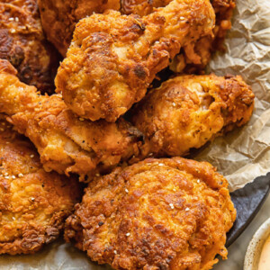Close up shot of buttermilk fried chicken drumsticks with crispy skin piled on a plate