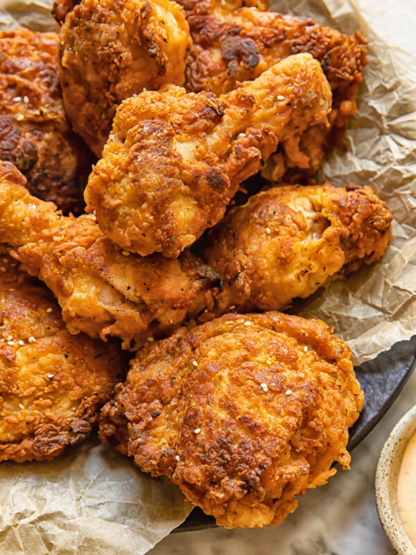 Close up shot of buttermilk fried chicken drumsticks with crispy skin piled on a plate