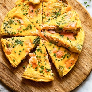 Top down shot of salmon frittata slices on a platter topped with herbs