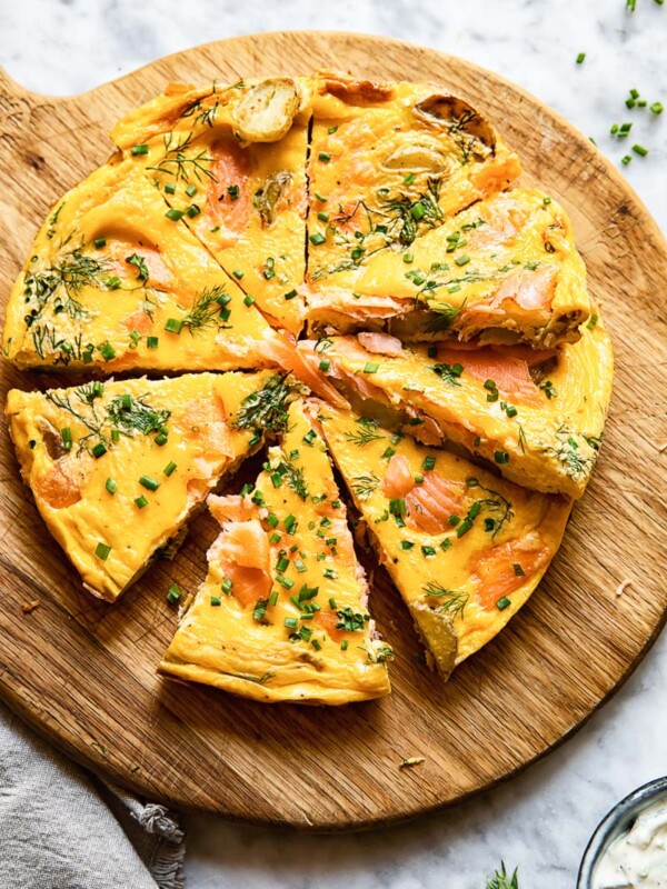 Top down shot of salmon frittata slices on a platter topped with herbs